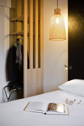 an open book on a bed with a lamp at ibis Styles Paris Buttes Chaumont in Paris