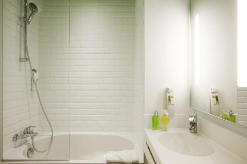 a bathroom with a shower and a tub and a sink at ibis Styles Paris Buttes Chaumont in Paris