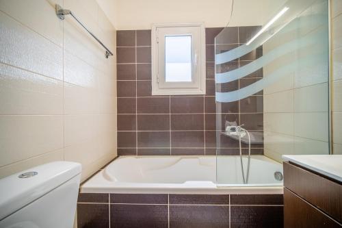 Un baño con bañera y ventana. en Country House with Private Balcony, en Gouvia