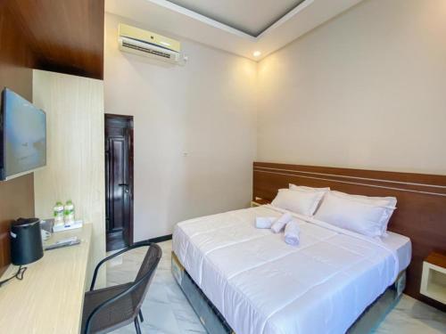 a bedroom with a large white bed and a chair at RedDoorz Plus @ Orange GH Diponogoro in Palangkaraya