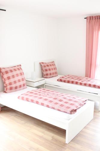 two beds in a room with red and white at Rendel-Apartments by Bismarck Hostel Öhringen in Öhringen