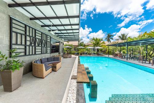 a swimming pool with couches and chairs next to a building at Banana Resort, le petit nid de Caro in Phumĭ R&eacute;ach Born