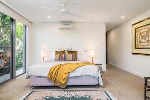 a bedroom with a bed and a ceiling fan at The Oasis Apartments and Treetop Houses in Byron Bay