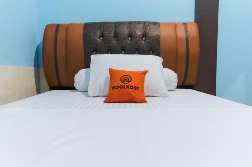 a bed with an orange pillow on top of it at KoolKost Syariah at Jelutung Jambi in Jambi