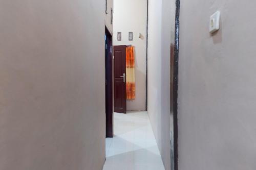 KoolKost Syariah at Jelutung Jambi في جامبي: ممر فارغ مع باب وغرفة بجدران بيضاء