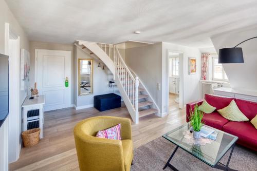a living room with a red couch and a staircase at Fitschen am Dorfteich in Wenningstedt