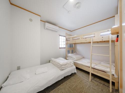 1 dormitorio con 2 literas y ventana en Super conveniently located The GUEST HOUSE HAKODATE BAY, en Hakodate