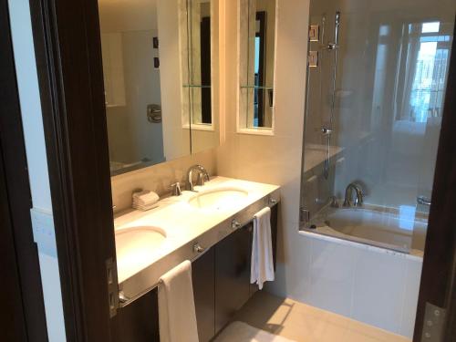 a bathroom with two sinks and a shower and a tub at Address fountain views apartments in Dubai