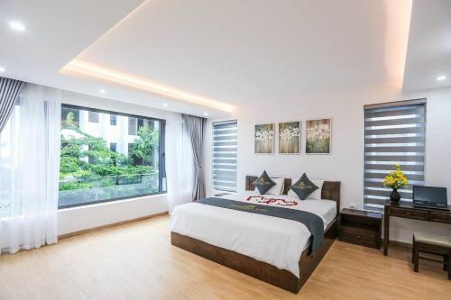 1 dormitorio con cama, escritorio y ventana en Sea Breeze Villa FLC sang trọng gần biển có bể bơi, en Sầm Sơn