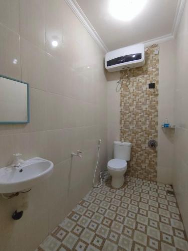 a bathroom with a white toilet and a sink at Sierra Homestay Malang 3 BR AC in Ngadipuro