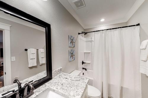 a bathroom with a sink and a mirror and a toilet at Beach Cottage South in Dauphin Island