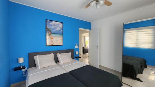 een blauwe slaapkamer met een bed en een blauwe muur bij Beautiful luxury villa with private pool in Palm-Eagle Beach