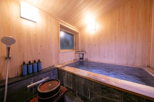 a hot tub in a wooden room with a wooden wall at Baien in Yufu