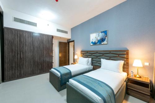 Habitación de hotel con 2 camas y ventana en Luxe Grand Hotel Apartments en Sharjah