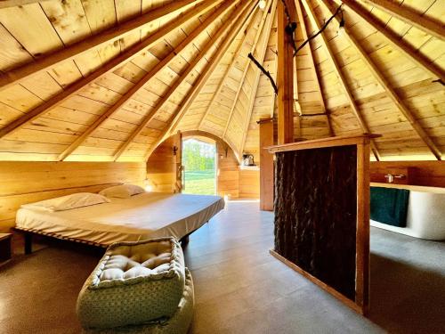 Großes Zimmer mit einem Bett in einer Holzhütte in der Unterkunft Domaine d'Escapa in Estipouy