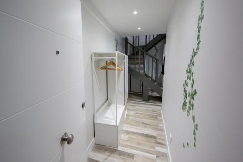 een hal met witte muren, houten vloeren en een trap bij Wind Rose 10 - Moderno duplex a estrenar in San Lorenzo de El Escorial