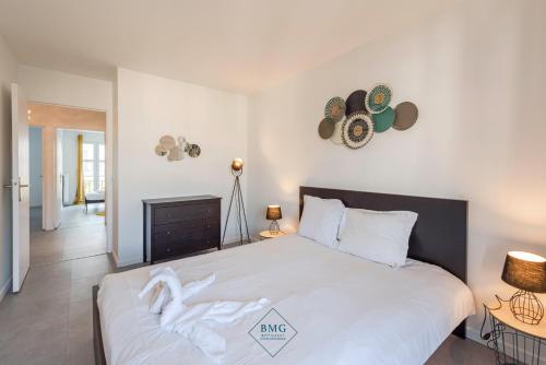 - une chambre dotée d'un grand lit blanc avec des chapeaux au mur dans l'établissement Résidence Val d'Europe Bmyguest, à Chessy