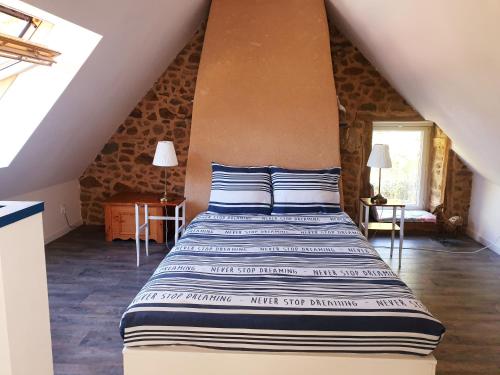 a bedroom with a bed with blue and white sheets at Gîte Le Valet, T2 classé 3 étoiles, entre Rennes et Saint-Malo in La Chapelle-aux-Filzméens