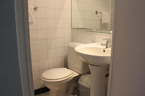 a white bathroom with a toilet and a sink at Hotel Excelsior in Paris