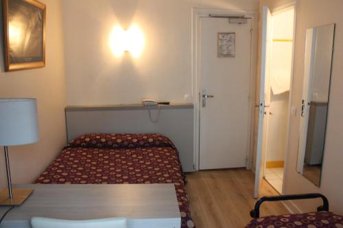 a small room with a bed and a light on the wall at Hotel Excelsior in Paris