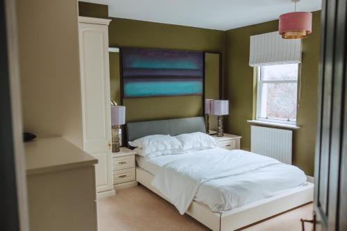 a bedroom with a white bed and a window at The Grange Matlock Bath in Matlock