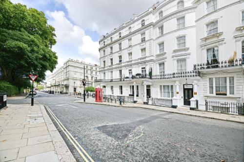an empty city street with white buildings and a red phone booth at The J Hyde Park in London
