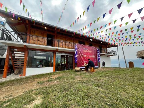 a man standing in front of a building with flags at Homestay Chân Mây Chiêu Lầu Thi in Hoàng Su Phì