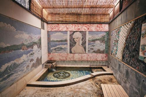 a bathroom with a tub with a painting on the wall at Nogami Honkan in Beppu