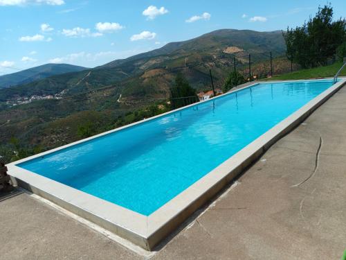 een groot zwembad met bergen op de achtergrond bij Casa das Oliveiras in Colmeal