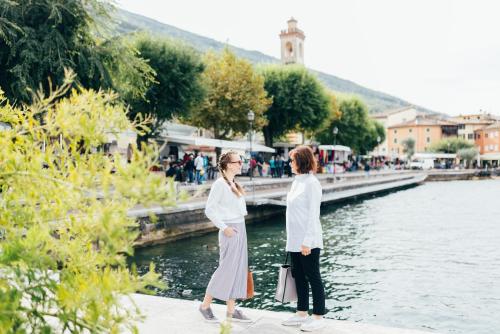 two women standing next to a body of water at Hotel Orione - Lake Front Hotel in Brenzone sul Garda