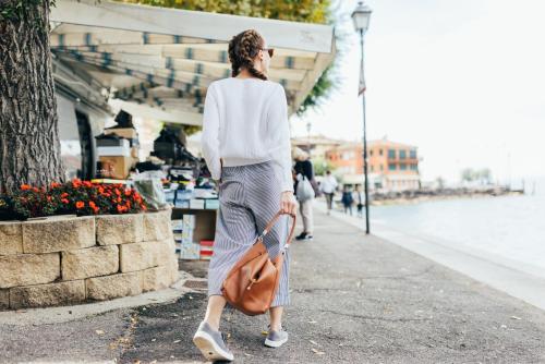 a woman walking down a sidewalk with a brown bag at Hotel Orione - Lake Front Hotel in Brenzone sul Garda