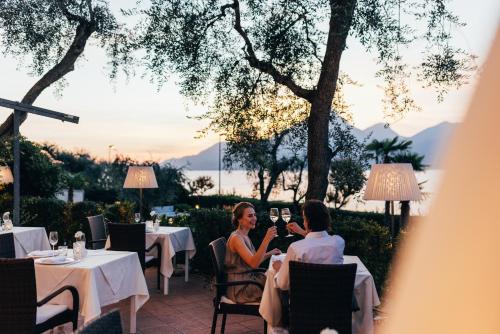 a man and woman sitting at a table at a restaurant at Hotel Orione - Lake Front Hotel in Brenzone sul Garda