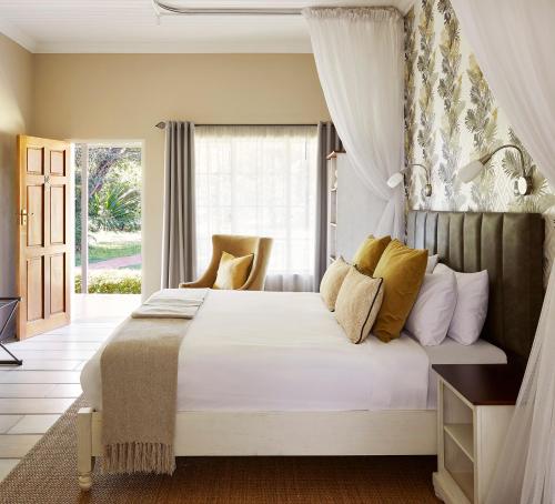 a bedroom with a large white bed with yellow pillows at Pioneers in Victoria Falls