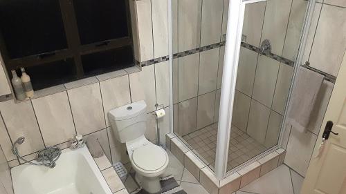 a small bathroom with a toilet and a shower at Trevi 11 in Shelly Beach