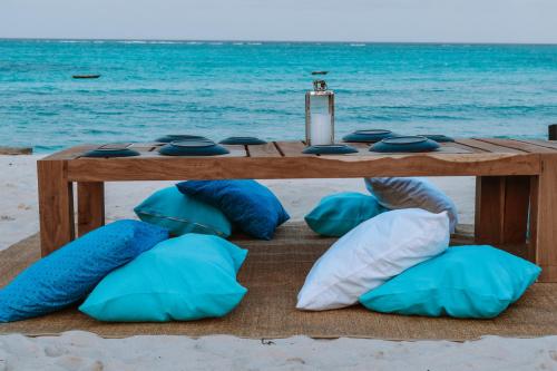 a table with pillows on the beach with the ocean at Safira Blu Luxury Resort & Villas in Nungwi