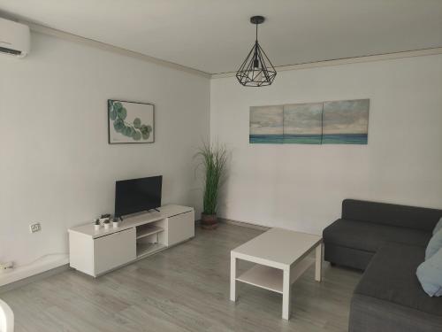 a white living room with a couch and a tv at Albir cosy apartment in Albir