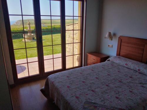 1 dormitorio con cama y ventana grande en La Morada del Cabo Peñas TEZAN - Gozón - Luanco, 