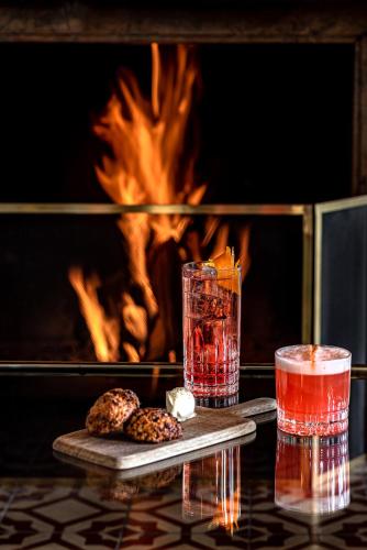 a table with two drinks and two cookies in front of a fireplace at Experimental Chalet in Verbier