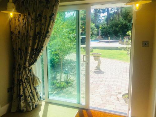 a sliding glass door with a view of a garden at Chadham Pines Cottage in Parkstone