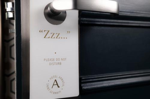 a white tag on a door with a sign on it at Hotel Abbatial Saint Germain in Paris