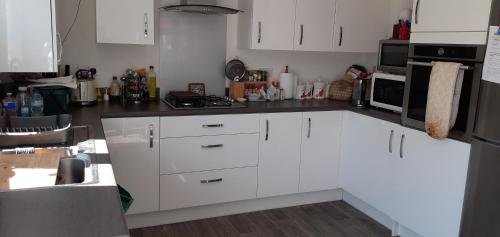 a kitchen with white cabinets and a black counter top at Beautiful En-suite room in Wokingham