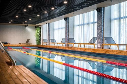 a swimming pool in a large room with windows at Divas Laivas apartments with a terrace in Ķesterciems
