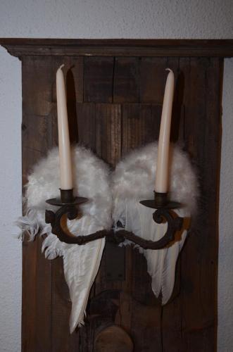 a chandelier with two white feathers and two candles at Hotel Belmont in Engelberg