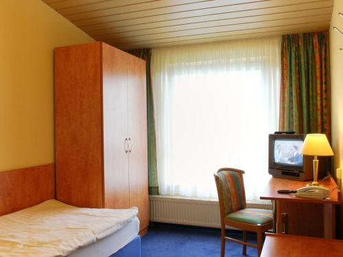 Schlafzimmer mit einem Bett, einem TV und einem Fenster in der Unterkunft Kärntner Stub'n in Königslutter am Elm