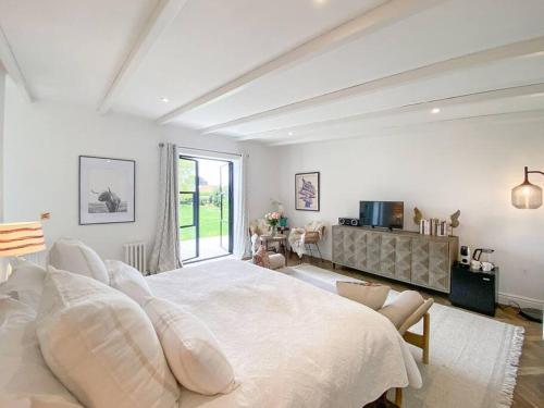 a white bedroom with a large bed and a window at Little Owl A beautiful bolt-hole for couples in Aldeburgh