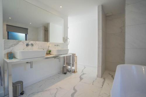 - une salle de bains blanche avec deux lavabos et un miroir dans l'établissement Hotel le Mandala, à Saint-Tropez