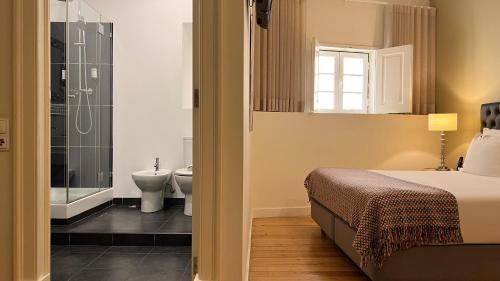 a bedroom with a bed and a bathroom with a shower at Casa do Bairro by Shiadu in Lisbon