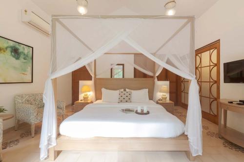 a bedroom with a white bed with a canopy at StayVista at Villa Arcadia with Alfresco Dining in Candolim