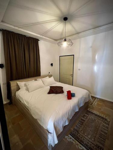 a bedroom with a large white bed with a red bag on it at סוויטה בכפר ירכא in Yarka