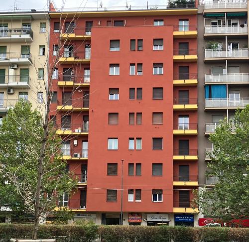 un grand bâtiment rouge avec balcon dans l'établissement Splendido Bilocale adiacente metro M5 - Ca Granda, à Milan